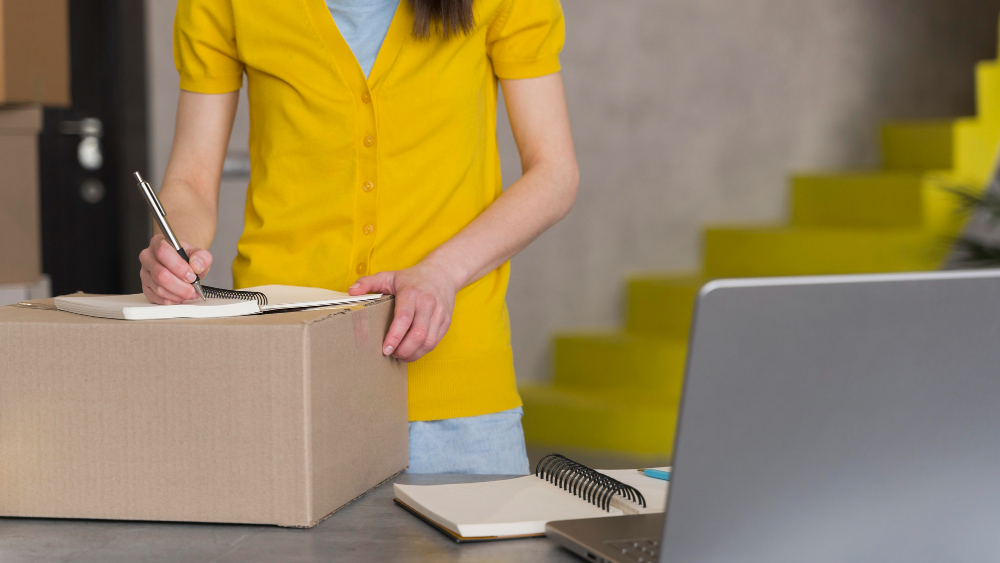 Mujer con paquete en la mesa y una laptop