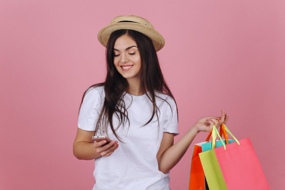 Mujer se va de compras y sujeta bolsas en la mano mientras mira su celular