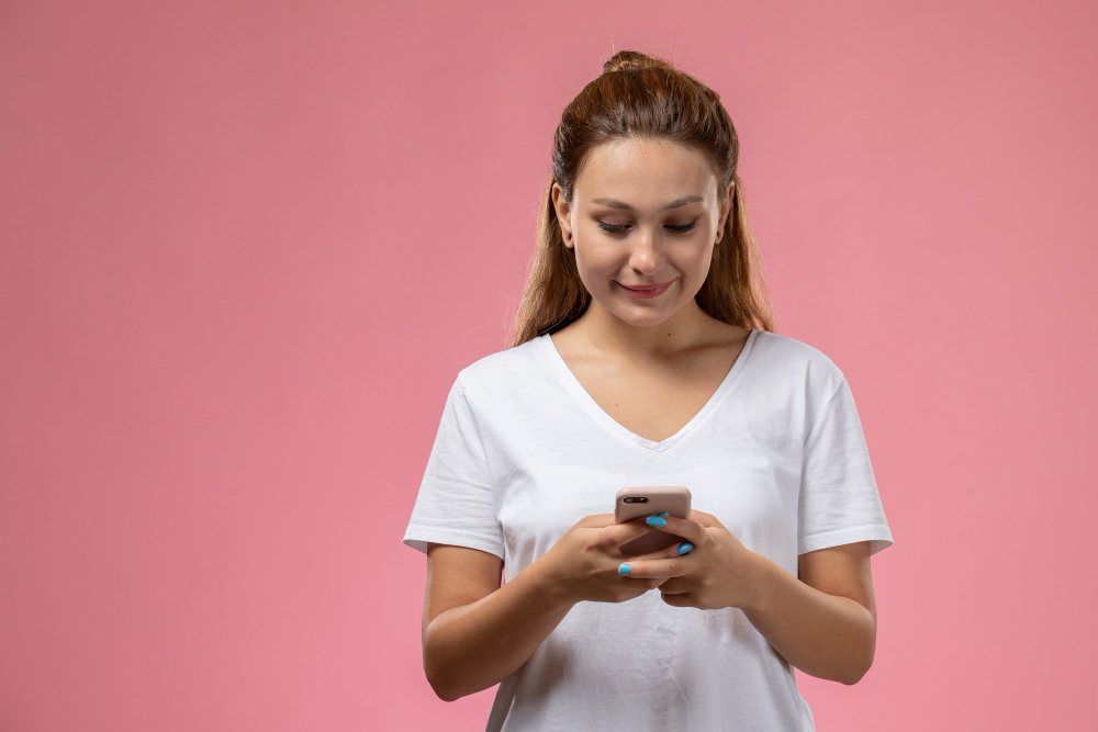 Mujer joven con playera blanca viendo su celular